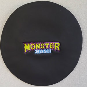 May include: Black round patch with the text "Monster Bash" in yellow, purple, and blue lettering.