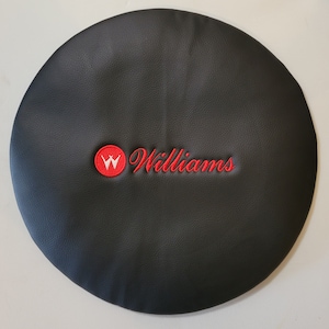 May include: Black leather round seat cushion with red embroidered text "Williams" and a red circle with a white "W" inside.