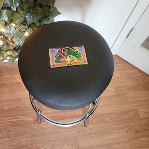 May include: A black bar stool with a chrome base and a circular seat. The seat has a colorful graphic of a dragon on it.