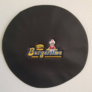 Könnte beinhalten: Schwarzer Leder-Patch mit gelbsticktem Text "Burgertime" und einem Cartoon-Koch, der einen Hamburger hält.