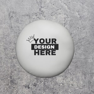 May include: White round sticker with a black crown and the text "YOUR DESIGN HERE" on a gray concrete background.