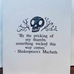 May include: A black and white illustration of a skull with a quote from Shakespeare's Macbeth: "By the pricking of my thumbs, something wicked this way comes."