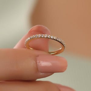 以下が含まれることがあります： 小さな透明なダイヤモンドが並んだ、細い金のバンドリングです。