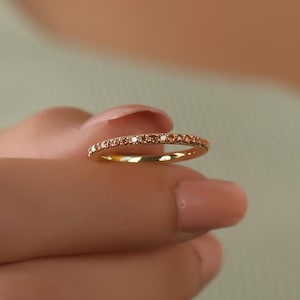 Könnte beinhalten: Ein zarter Goldring mit einer Reihe kleiner, funkelnder Diamanten.