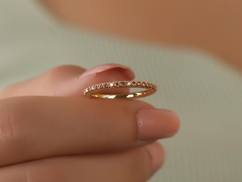 Puede incluir: Un delicado anillo de banda de oro con una fila de peque&ntilde;os diamantes brillantes.