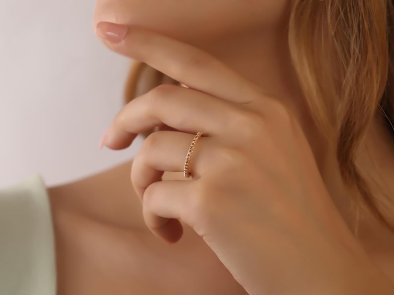 Puede incluir: Un anillo de banda de oro con peque&ntilde;as piedras redondas engastadas en una l&iacute;nea continua alrededor de la banda.