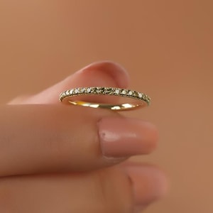 Può includere: Una sottile fascia d'oro con una fila di piccoli diamanti incastonati a pavé.