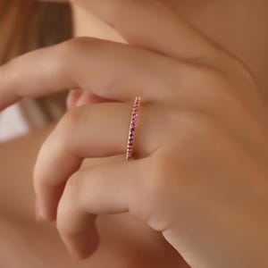 K&ouml;nnte beinhalten: Ein zarter Goldring mit einer Reihe kleiner rosafarbener Edelsteine.