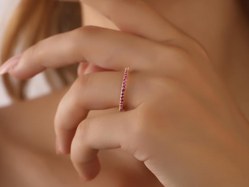 K&ouml;nnte beinhalten: Ein zarter Goldring mit einer Reihe kleiner rosafarbener Edelsteine.