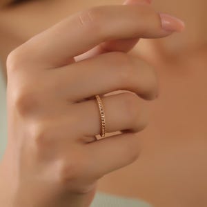 Puede incluir: Un fino anillo de banda de oro con un dise&ntilde;o delicado y brillante.