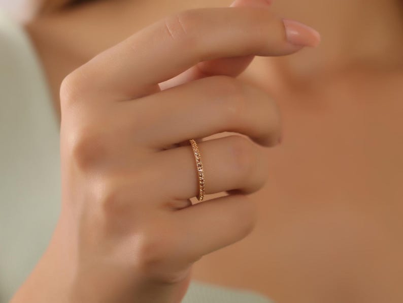 Puede incluir: Un fino anillo de banda de oro con un dise&ntilde;o delicado y brillante.