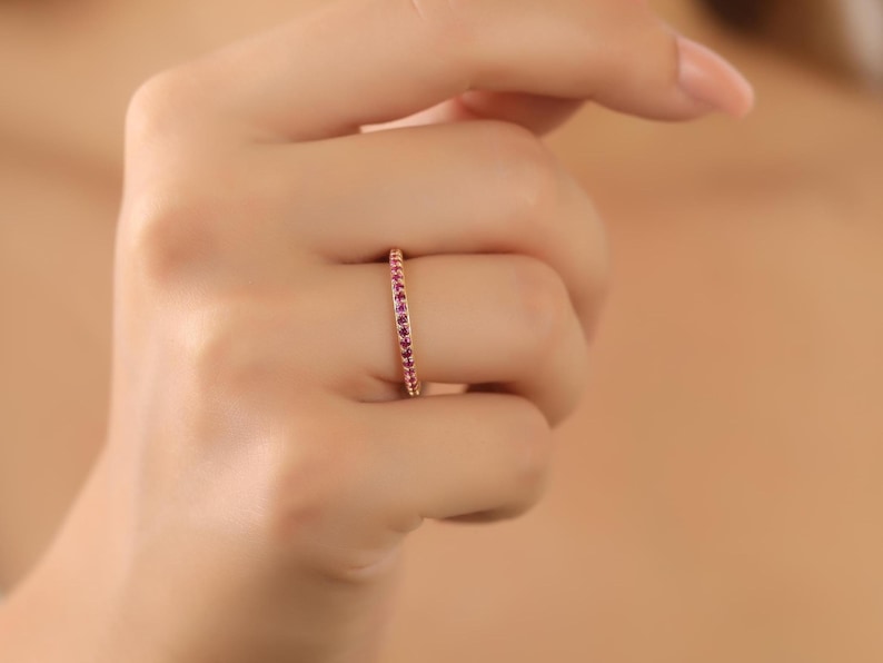 K&ouml;nnte beinhalten: Ein zarter Goldring mit einer Reihe kleiner rosafarbener Edelsteine.