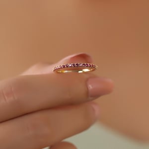 K&ouml;nnte beinhalten: Ein zarter Goldring mit einer Reihe kleiner rosafarbener Edelsteine.