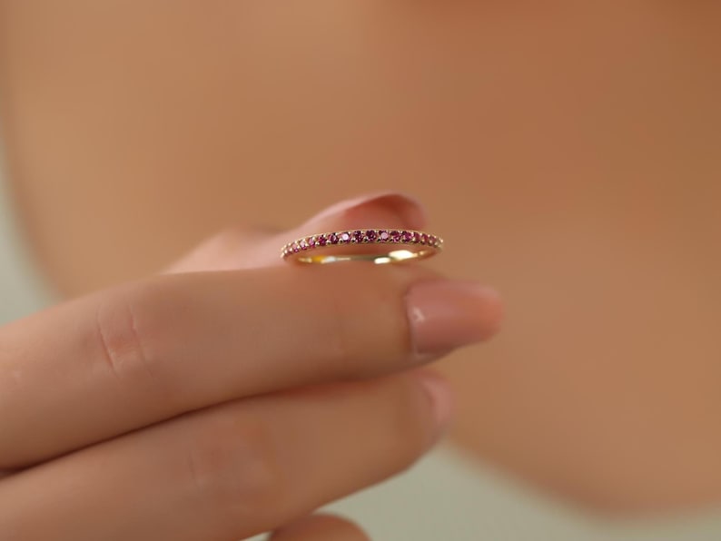 K&ouml;nnte beinhalten: Ein zarter Goldring mit einer Reihe kleiner rosafarbener Edelsteine.