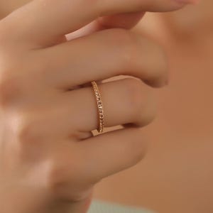 Puede incluir: Un fino anillo de banda de oro con una superficie texturizada.