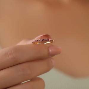 K&ouml;nnte beinhalten: Ein zarter Goldring mit einer Reihe kleiner rosafarbener Edelsteine.