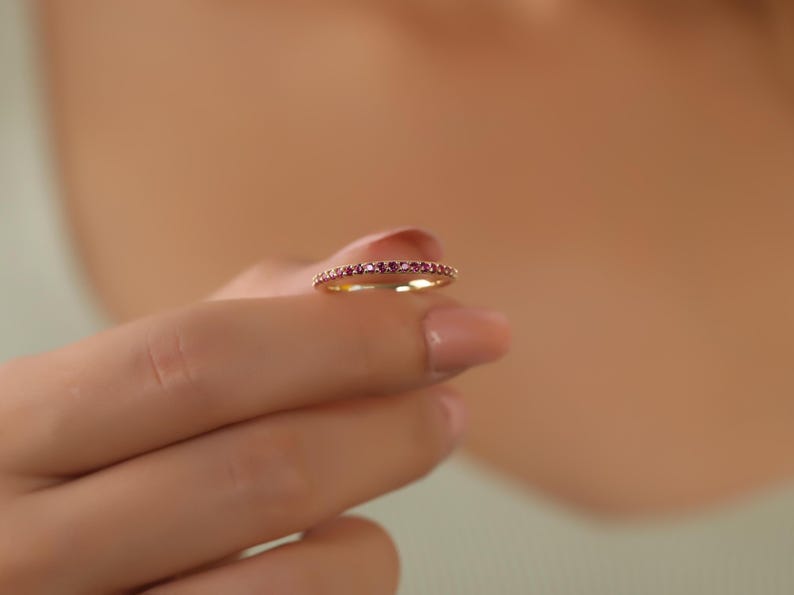 K&ouml;nnte beinhalten: Ein zarter Goldring mit einer Reihe kleiner rosafarbener Edelsteine.