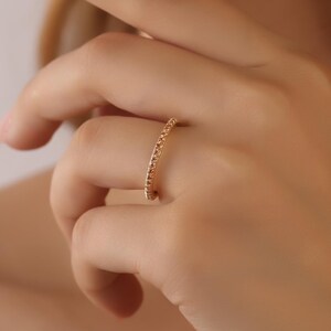 Puede incluir: Un delicado anillo de banda de oro con peque&ntilde;as piedras brillantes engastadas en una l&iacute;nea continua alrededor de la banda.