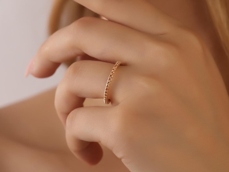 Puede incluir: Un delicado anillo de banda de oro con peque&ntilde;as piedras brillantes engastadas en una l&iacute;nea continua alrededor de la banda.