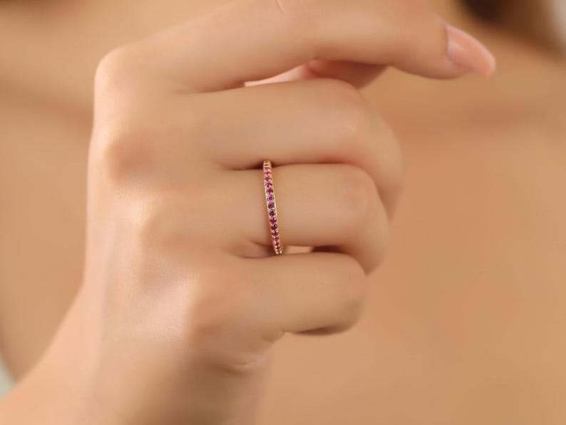 K&ouml;nnte beinhalten: Ein zarter Goldring mit einer Reihe kleiner rosafarbener Edelsteine.