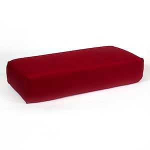 May include: A rectangular red cushion with a smooth, even surface. The cushion is made of a soft, plush fabric.