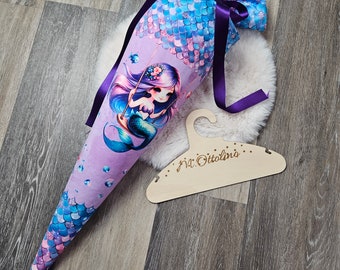 May include: Purple and blue mermaid school cone with a purple ribbon and a wooden hanger with the name "M. Ottolina" written on it.