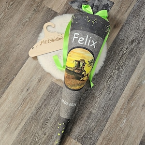 Könnte beinhalten: Ein schwarzer und grüner Schultüte mit einem Bild eines Mähdreschers und dem Namen "Felix" darauf. Die Tüte hat ein grünes Band und das Datum "04.09.2024" ist darauf gedruckt.