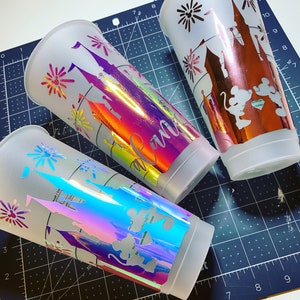 Puede incluir: Tres vasos de pl&aacute;stico blanco con acabado mate. Cada vaso tiene un dise&ntilde;o de vinilo iridiscente diferente que presenta un castillo, fuegos artificiales y personajes de Mickey Mouse. Los dise&ntilde;os est&aacute;n recortados y el vinilo es de color hologr&aacute;fico iridiscente.