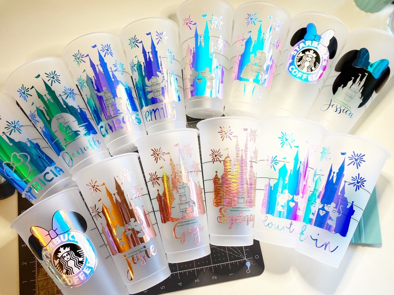Puede incluir: Una colecci&oacute;n de 10 vasos de pl&aacute;stico transparentes con dise&ntilde;os coloridos e iridiscentes del castillo de Cenicienta y fuegos artificiales. Cada vaso tiene un nombre diferente escrito en &eacute;l, incluyendo "Jessica", "Emily", "Chris", "Danielle", "Alicia", "Jessie", "Sydney", "Courtney" y "Bout & In".