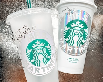 May include: Two white reusable coffee cups with a green Starbucks logo and the text "future Mrs. Martinez" on one cup and "Mrs. Martinez" on the other cup. The cups are made in the USA and are reusable, recyclable, and re-enjoyable.
