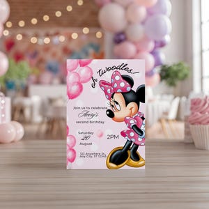 Op de afbeelding: Een roze uitnodigingskaart met Minnie Mouse in een polkadot jurk en strik. De kaart kondigt Avery's tweede verjaardag aan, met datum, tijd en locatie. Ballonnen en een cupcake staan op de achtergrond.