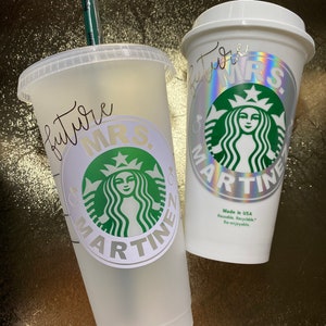 Op de afbeelding: Twee witte herbruikbare bekers met een groen Starbucks-logo en de tekst "future MRS. MARTINE" erop. De bekers zijn gemaakt in de VS en zijn herbruikbaar, recyclebaar en opnieuw te gebruiken.