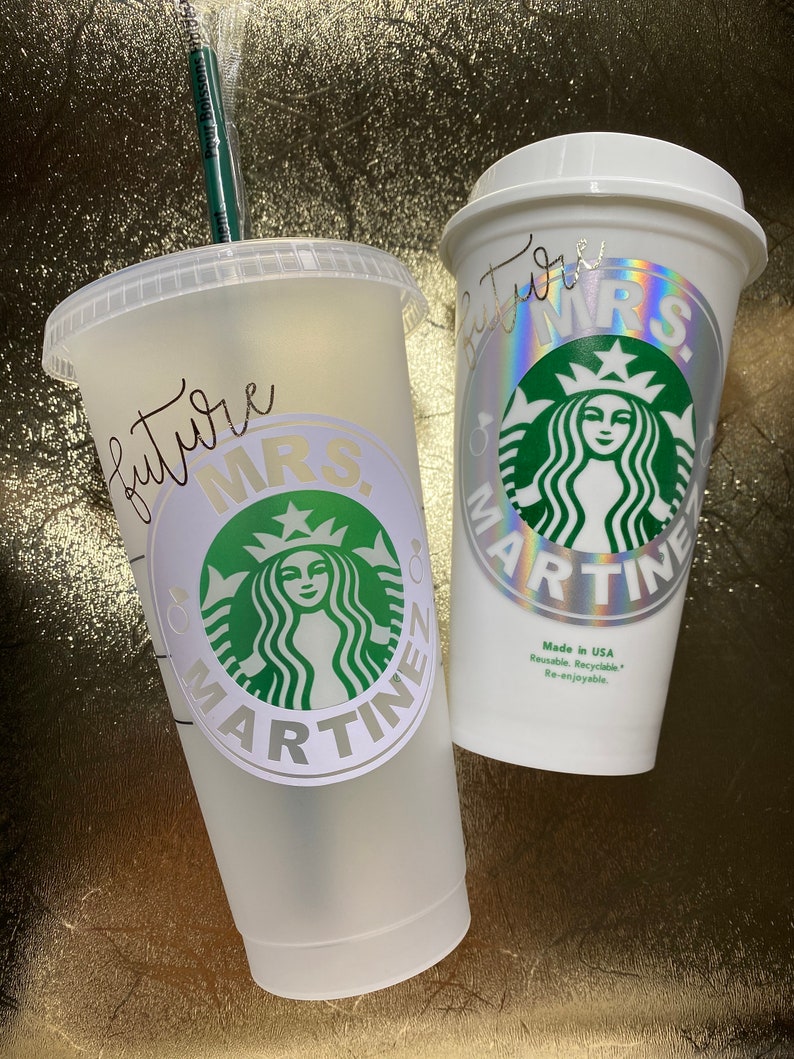 Op de afbeelding: Twee witte herbruikbare bekers met een groen Starbucks-logo en de tekst "future MRS. MARTINE" erop. De bekers zijn gemaakt in de VS en zijn herbruikbaar, recyclebaar en opnieuw te gebruiken.