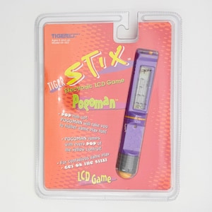 以下が含まれることがあります： タイガーエレクトロニクスのStix Pogoman LCDゲームのビンテージ品。オリジナルのパッケージ入り。ゲームは紫で、小さなLCDスクリーンが付いています。パッケージはオレンジと赤で、ゲームの説明が記載されています。