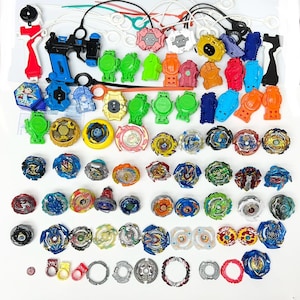 Puede incluir: Una colección de coloridos juguetes de peonzas y lanzadores. Las peonzas presentan varios diseños y colores, incluyendo azul, verde, amarillo y rojo. Los lanzadores son azules, rojos y negros. Accesorios: cuerdas de tracción y componentes de plástico.