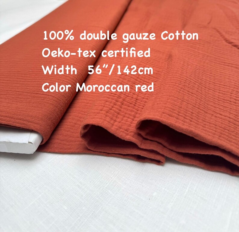 May include: A roll of Moroccan red double gauze cotton fabric. The fabric is 56 inches wide and Oeko-tex certified. The image includes the text: 100% double gauze Cotton, Oeko-tex certified, Width 56"/142cm, Color Moroccan red.