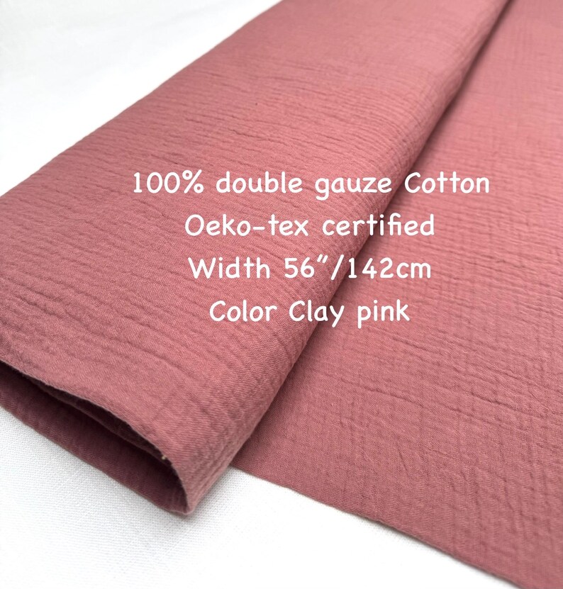 May include: A folded piece of clay pink double gauze cotton fabric. The fabric is 56 inches wide and Oeko-tex certified. The text on the fabric reads: "100% double gauze Cotton, Oeko-tex certified, Width 56"/142cm, Color Clay pink."