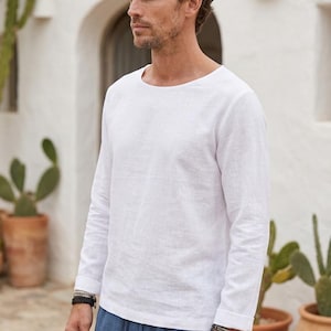 Op de afbeelding: Een wit shirt met lange mouwen en een ronde halslijn, gecombineerd met een blauwe broek met trekkoord. Het shirt heeft een eenvoudig ontwerp met omgeslagen mouwen, terwijl de broek een relaxte pasvorm heeft met een zichtbaar trekkoord in de taille.