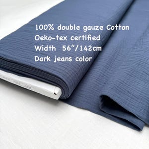 May include: A roll of dark jeans color 100% double gauze cotton fabric. The fabric is Oeko-tex certified and is 56 inches wide. The text on the fabric reads "100% double gauze Cotton", "Oeko-tex certified", "Width 56"/142cm", and "Dark jeans color".