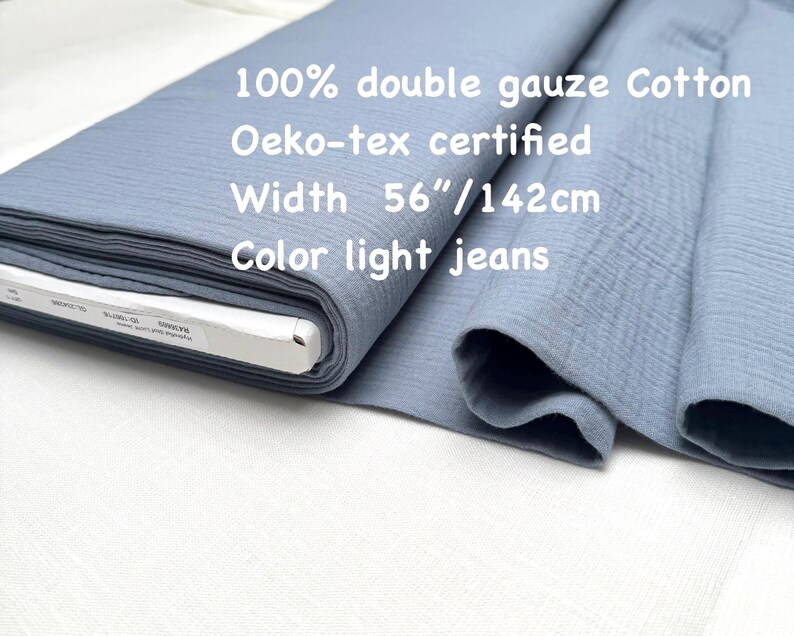 May include: A roll of light blue double gauze cotton fabric. The fabric is 56 inches wide and is Oeko-tex certified. The text on the fabric reads "100% double gauze Cotton", "Oeko-tex certified", "Width 56"/142cm", and "Color light jeans".