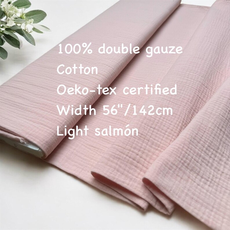 May include: Light salmon-colored double gauze fabric. The fabric is 100% cotton and Oeko-tex certified. The width is 56 inches. The text on the fabric reads: 100% double gauze, Cotton, Oeko-tex certified, Width 56"/142cm, Light salm&oacute;n.
