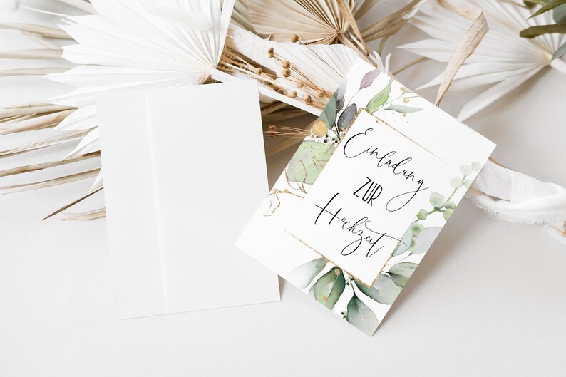 May include: A white card with gold accents and green watercolor leaves. The card says "Einladung zur Hochzeit" which translates to "Invitation to the Wedding" in English.