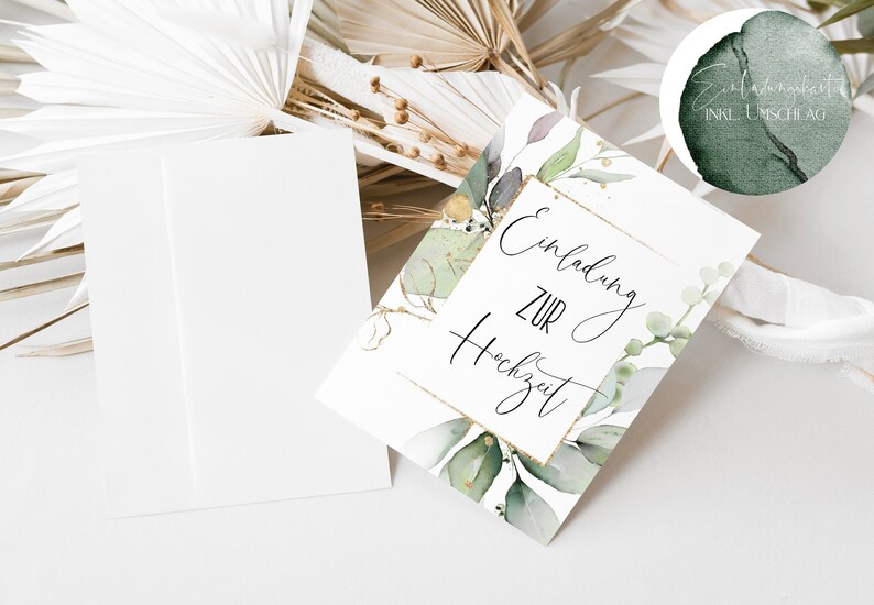 May include: A white card with gold trim and green watercolor leaves. The text on the card reads "Einladung zur Hochzeit" which translates to "Invitation to the Wedding" in English.