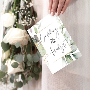 May include: A white card with gold lettering that says "Einladung zur Hochzeit" surrounded by green watercolor leaves.