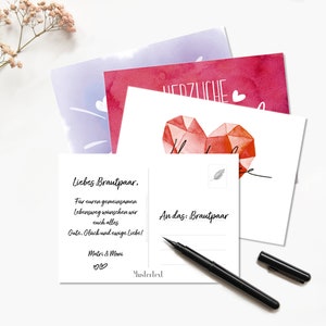May include: A white postcard with a red watercolor heart and the text "Liebes Brautpaar, Far euren gemeinsamen Lebensweg w&uuml;nschen wir euch alles Gute, Gl&uuml;ck und ewige Liebe! Matri & Moni ♡♡ Mustertext An das: Brautpaar"