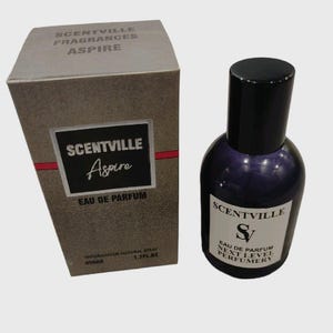 May include: A brown box with the text "SCENTVILLE FRAGRANCES ASPIRE" on the top and "SCENTVILLE Aspire EAU DE PARFUM" on the front. The box is next to a clear glass bottle with a black cap and a purple liquid. The bottle has the text "SCENTVILLE S EAU DE PARFUM NEXT LEVEL PERFUMERY" on the label.