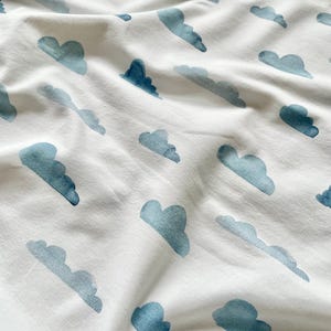 Könnte beinhalten: Weißer Stoff mit einem sich wiederholenden Muster aus blauen Aquarellwolken.