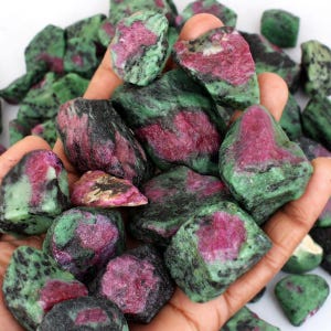 Può includere: Una collezione di pietre grezze di rubino in zoisite con un mix di vivaci cristalli di rubino color magenta-rosa incastonati in una matrice di zoisite verde scuro e nera. Questi esemplari minerali naturali non lucidati presentano forme irregolari.