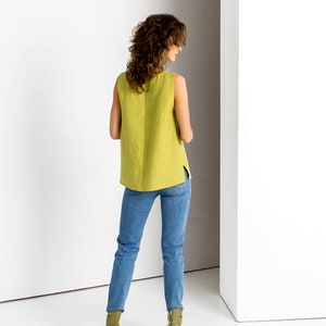 Back view of a Chartreuse linen tank top with side slits, styled with blue jeans and olive ankle boots