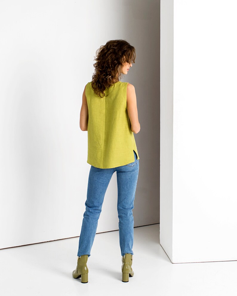 Back view of a Chartreuse linen tank top with side slits, styled with blue jeans and olive ankle boots
